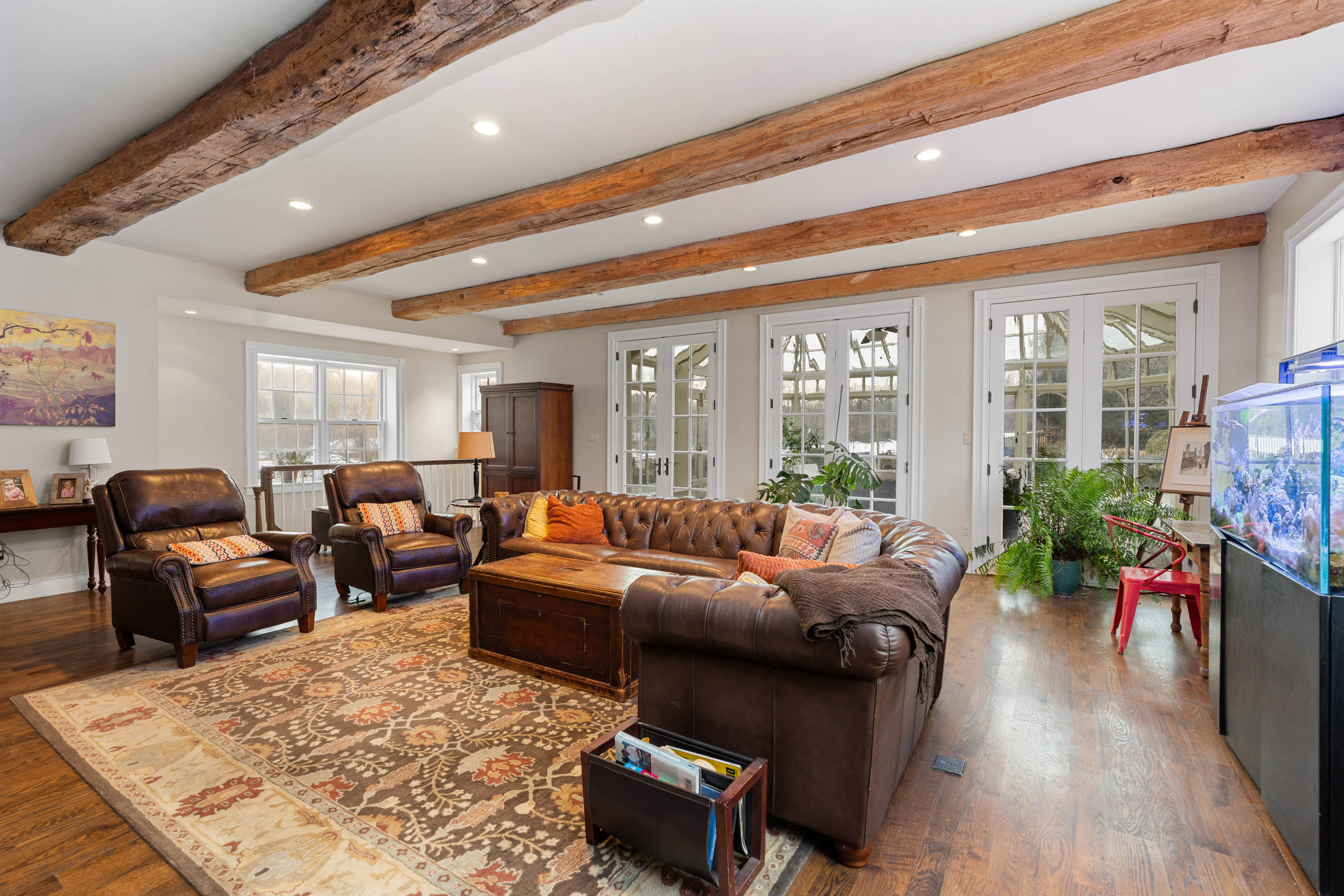 15314 PRICEVILLE ROAD, SPARKS GLENCOE, MD 21152 – Sunlit family room with exposed wood ceiling beams, leather seating, and hardwood floors in a historic stone manor