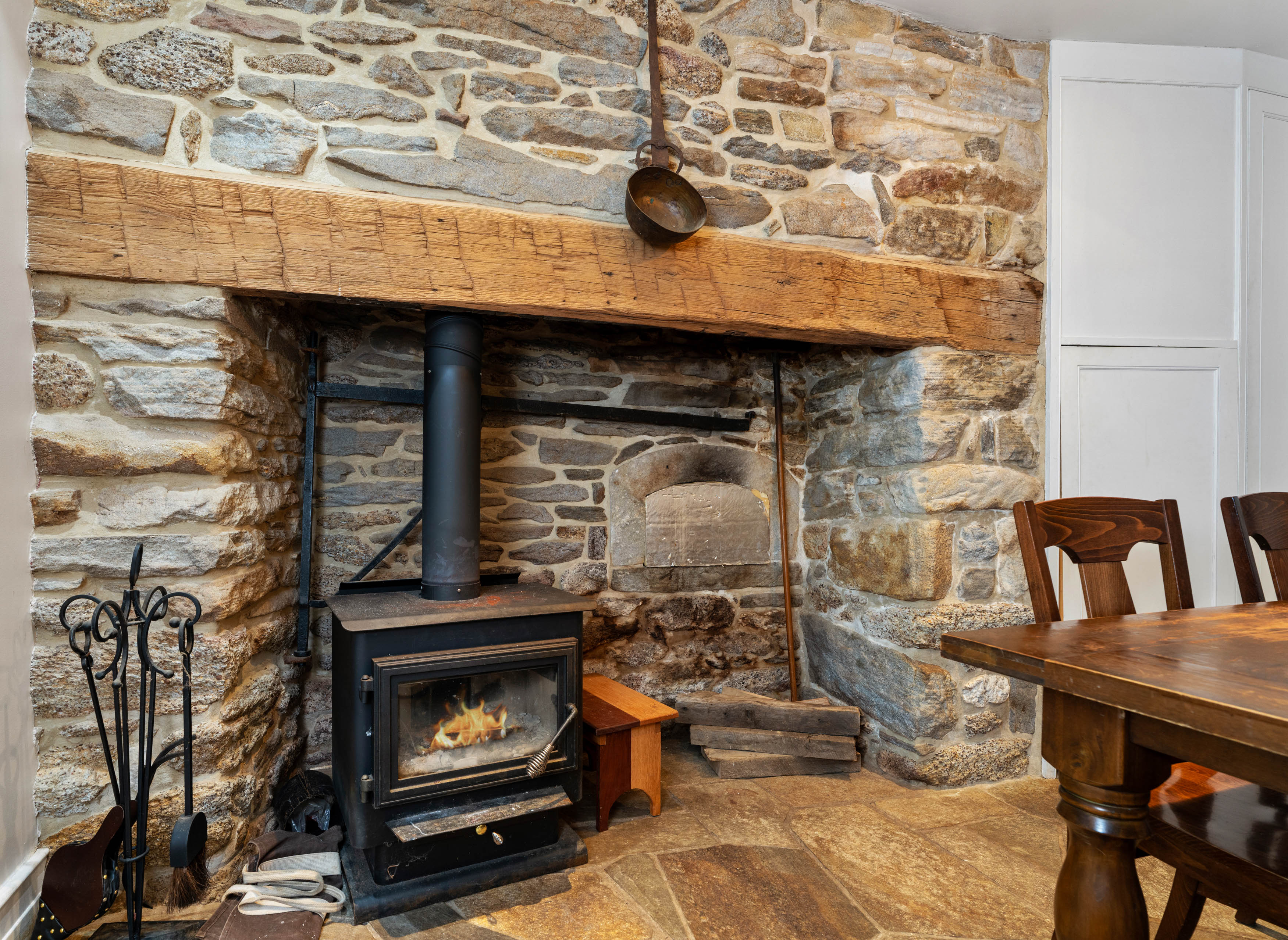15314 PRICEVILLE ROAD, SPARKS GLENCOE, MD 21152 – Exposed stone wall and wood-burning stove set within a fireplace beneath a rustic timber mantel