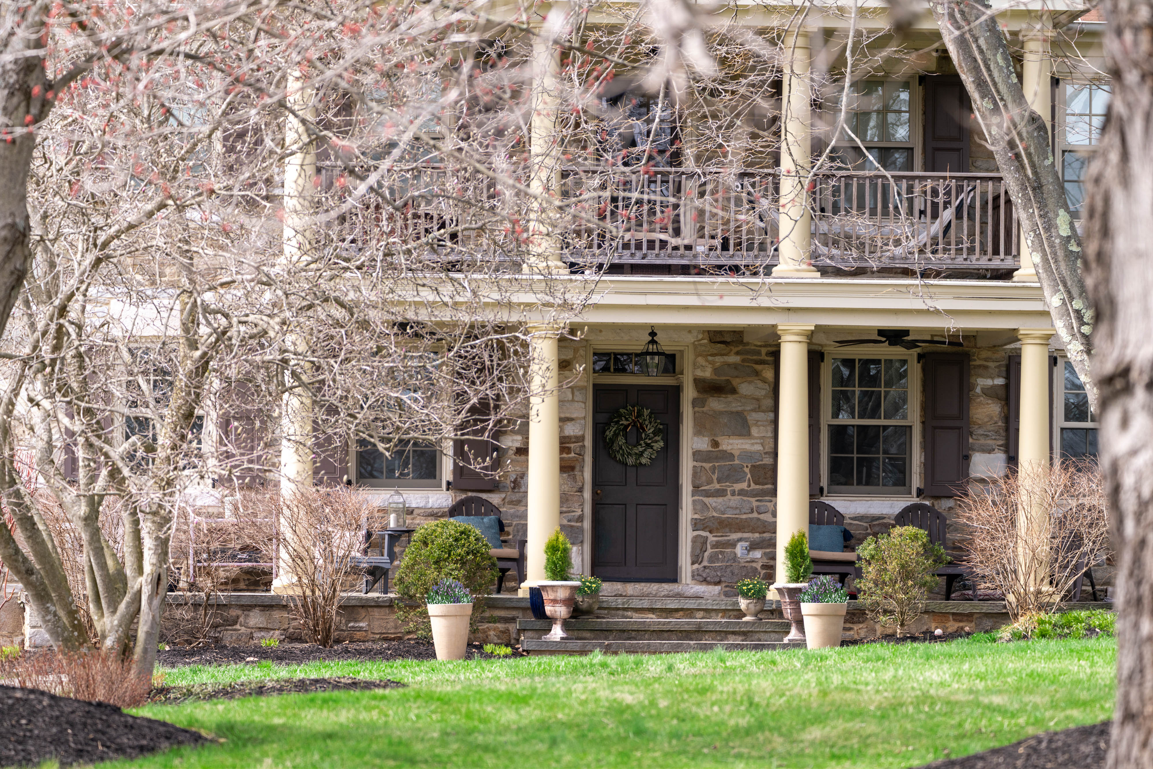 15314 PRICEVILLE ROAD, SPARKS GLENCOE, MD 21152 – Front elevation of historic stone manor with columned two-story porch framed by mature trees and green lawn